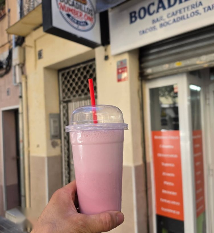 Batido rosa con pajita roja delante de la puerta del local