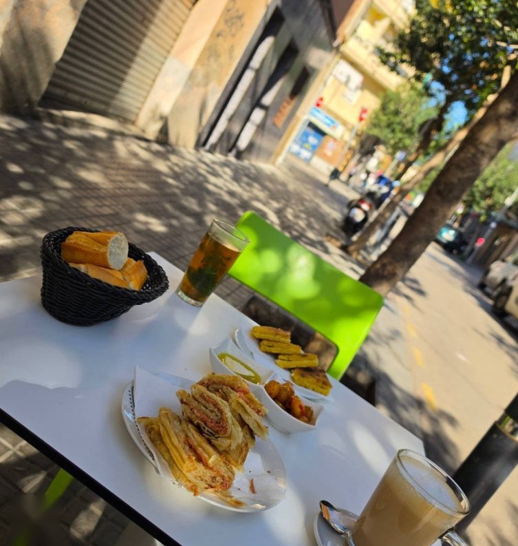 Desayuno marroquí en una mesa de la terraza, con la calle al fondo