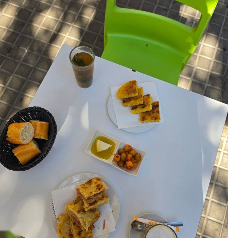 Mesa vista desde arriba con harcha, msemen, pan, aceitunas y té con menta