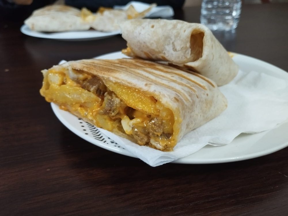 Taco a la plancha abierto, relleno de carne, patatas fritas y queso fundido