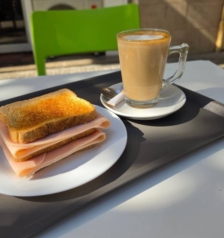Tostada con jamón York y café con leche sobre una bandeja